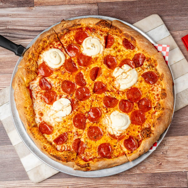 Pepperoni and ricotta cheese pizza on a metal pan with a red napkin and gold fork.